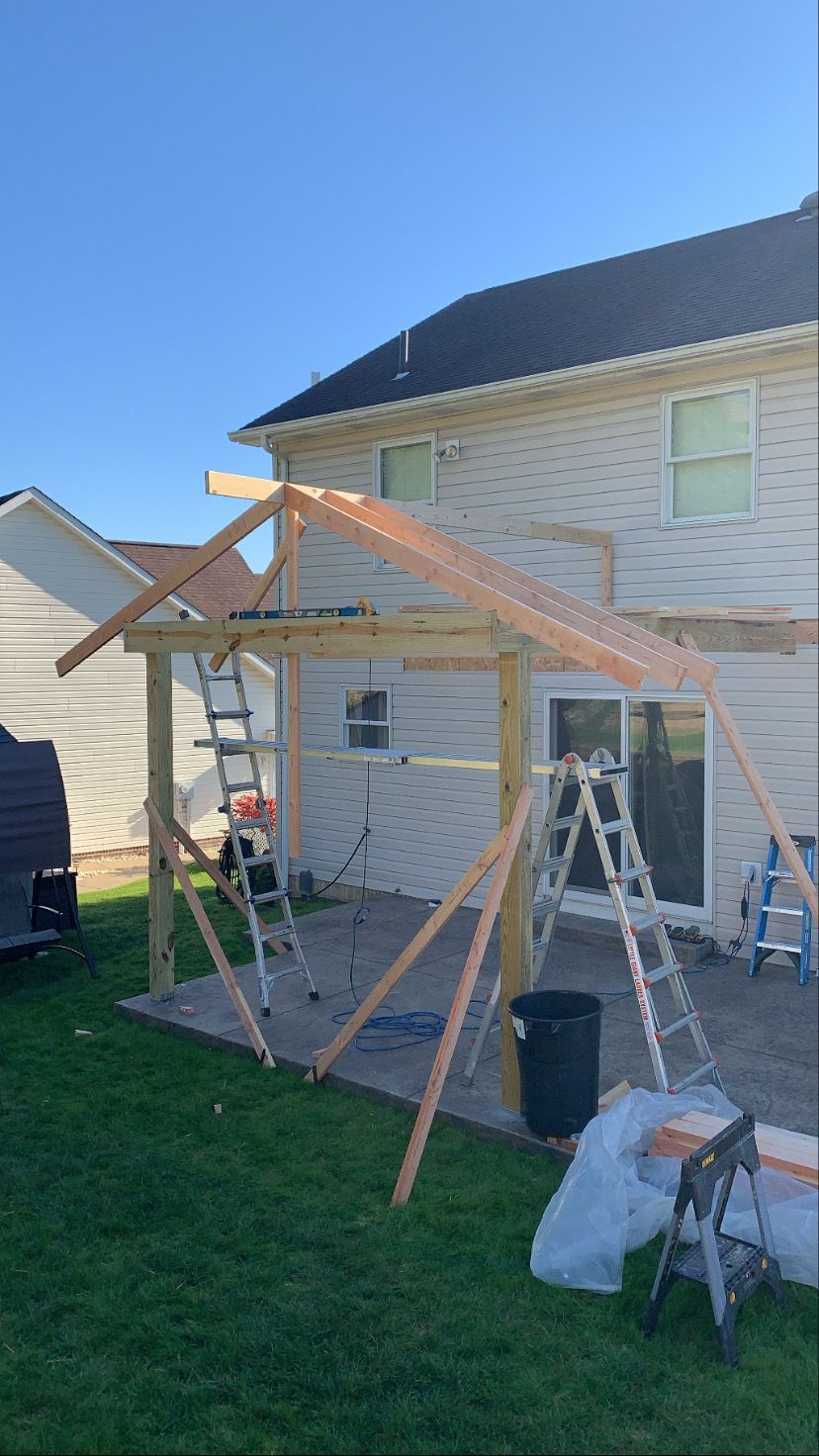 Construction of a wooden patio cover. The structure is partially built outdoors, on a patio.