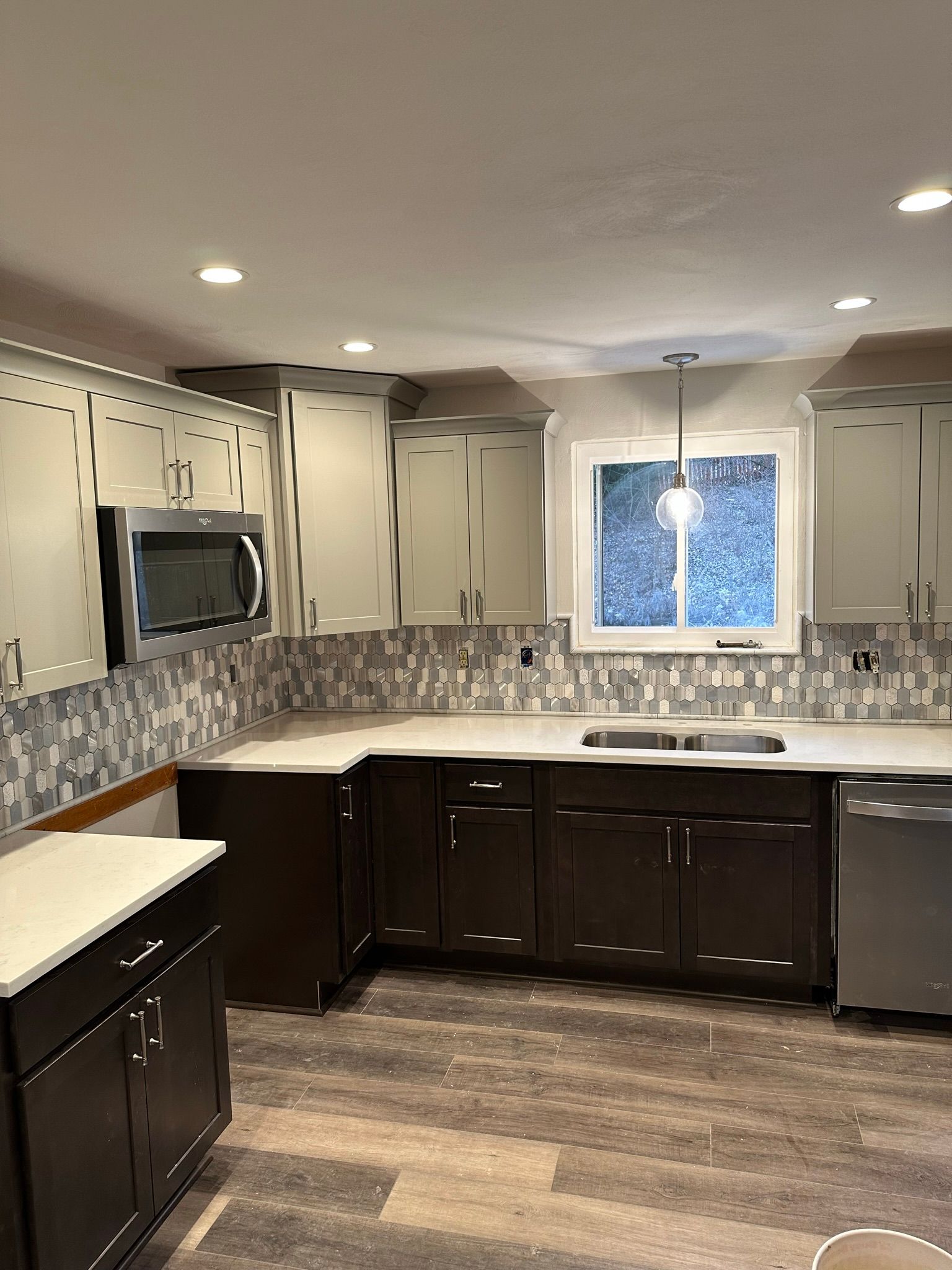 Kitchen renovation: dark brown cabinets, white countertops, mosaic backsplash, stainless steel appliances.