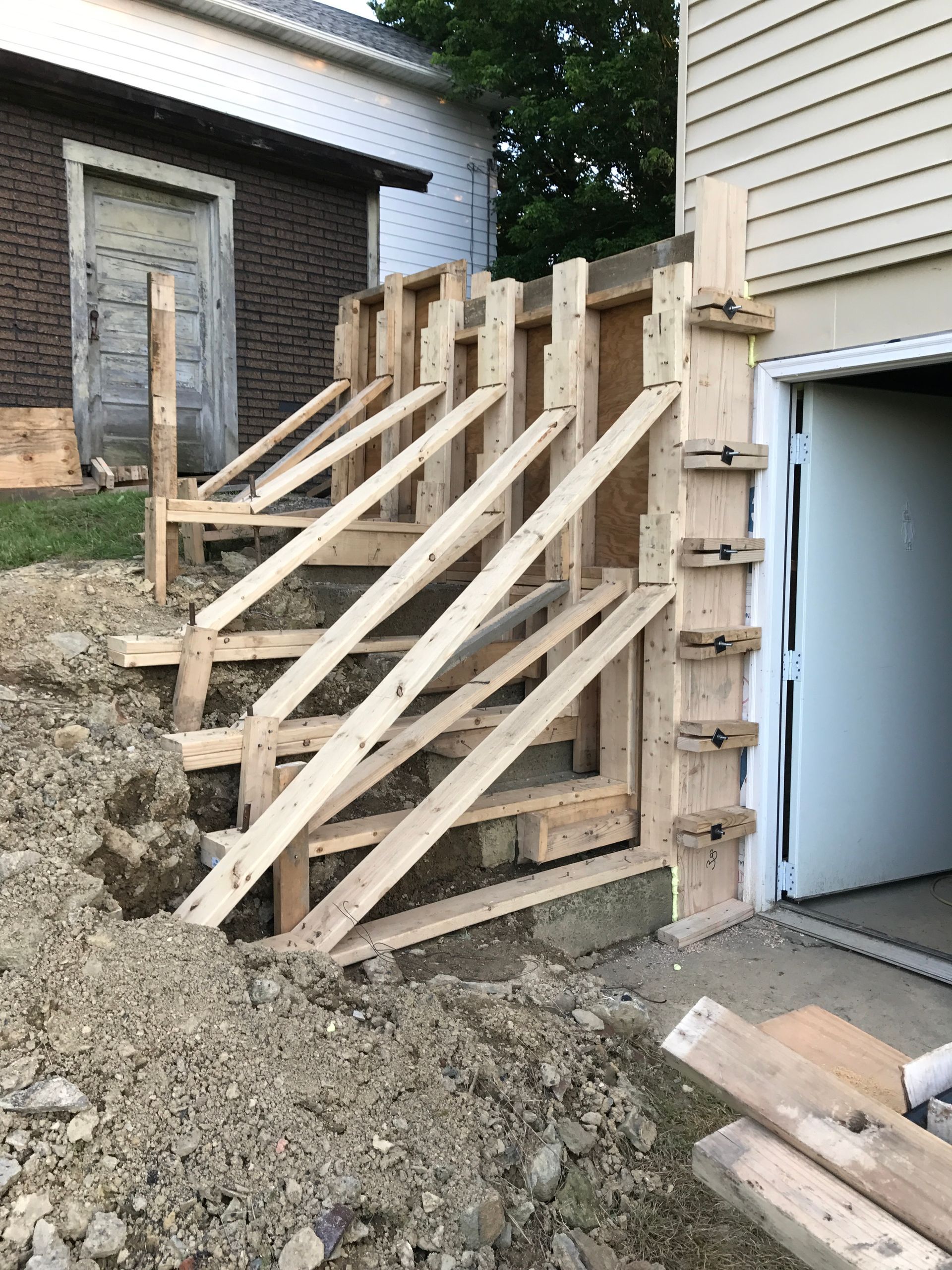 Wooden forms for concrete stairs construction next to a garage door.