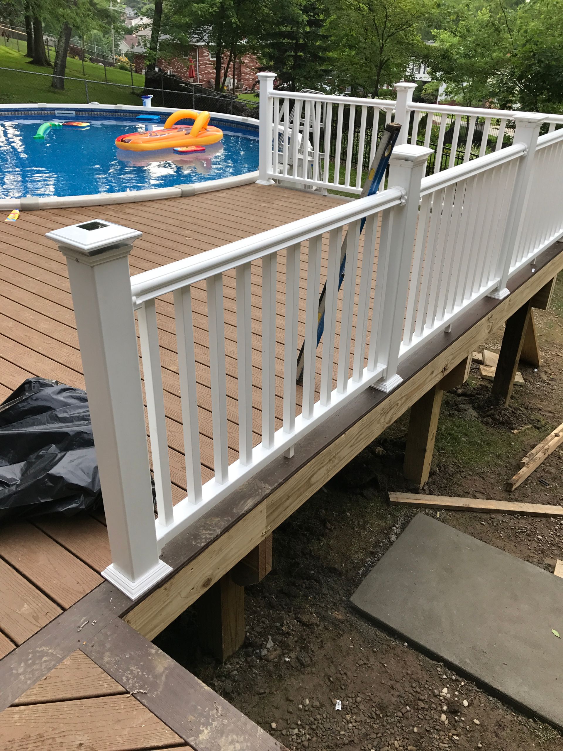 White railing on a composite deck overlooking a swimming pool.