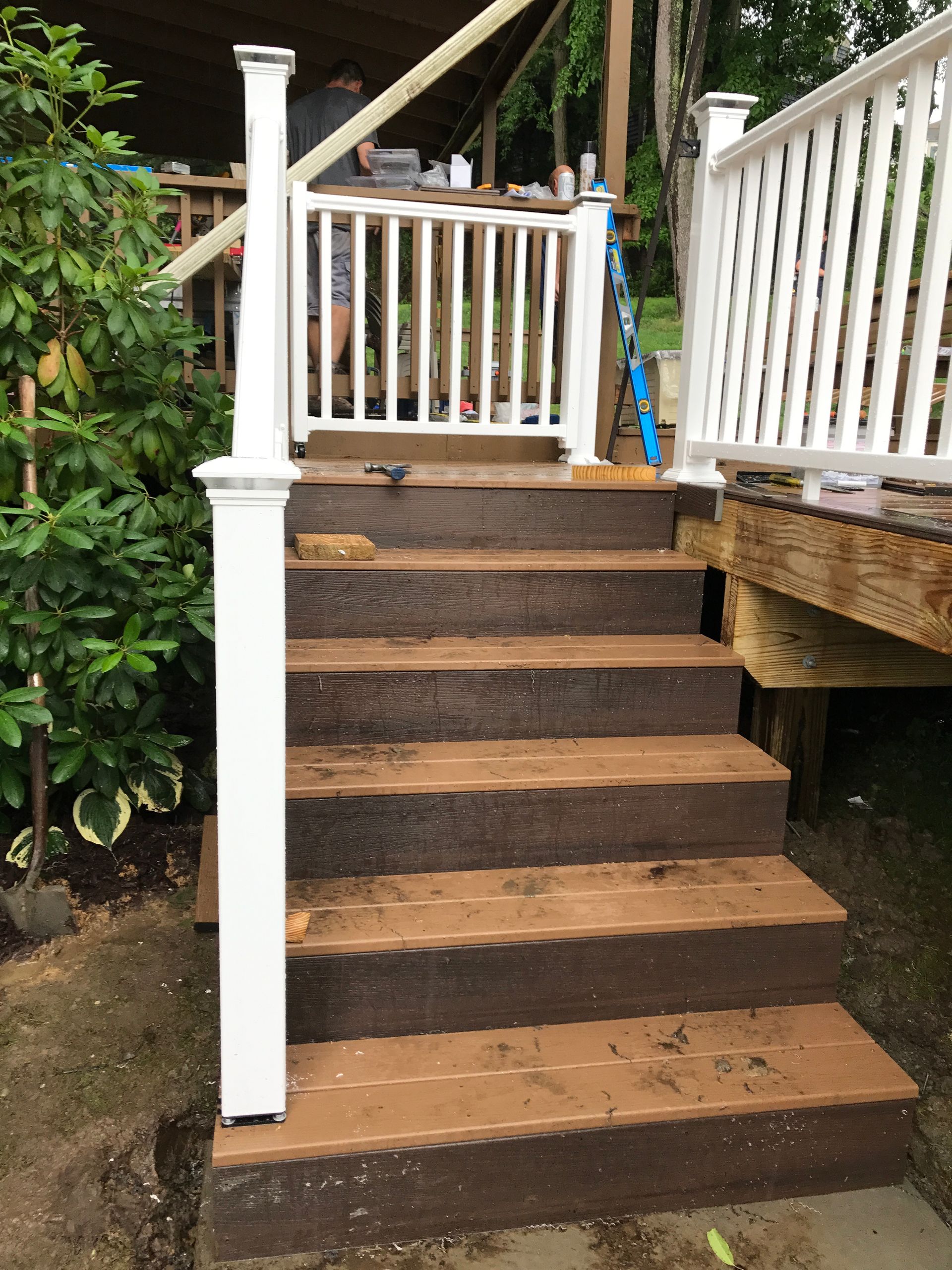 Wooden deck steps with white railing, a person in the background.