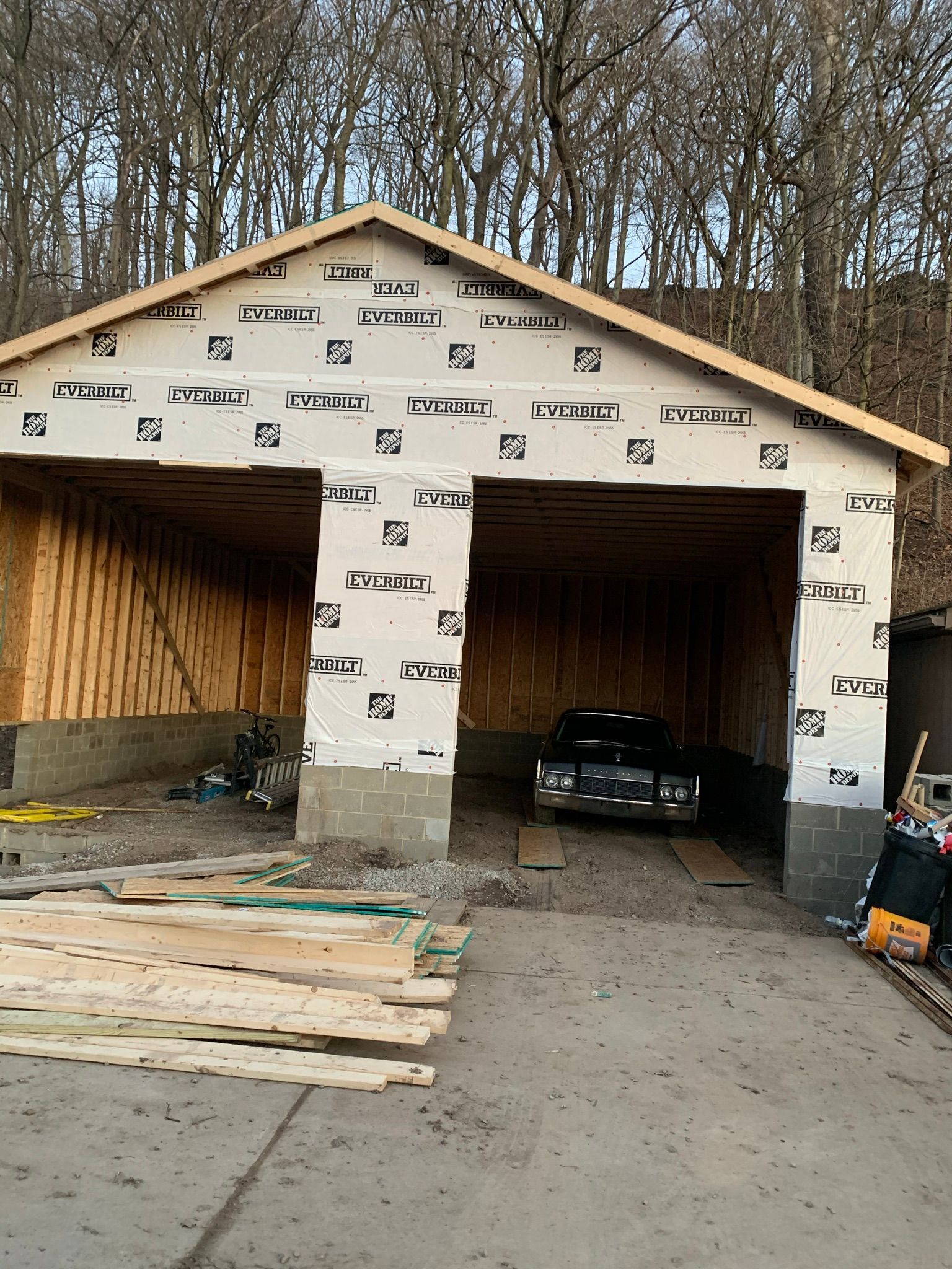 Garage under construction with a car inside, wood and gray blocks.