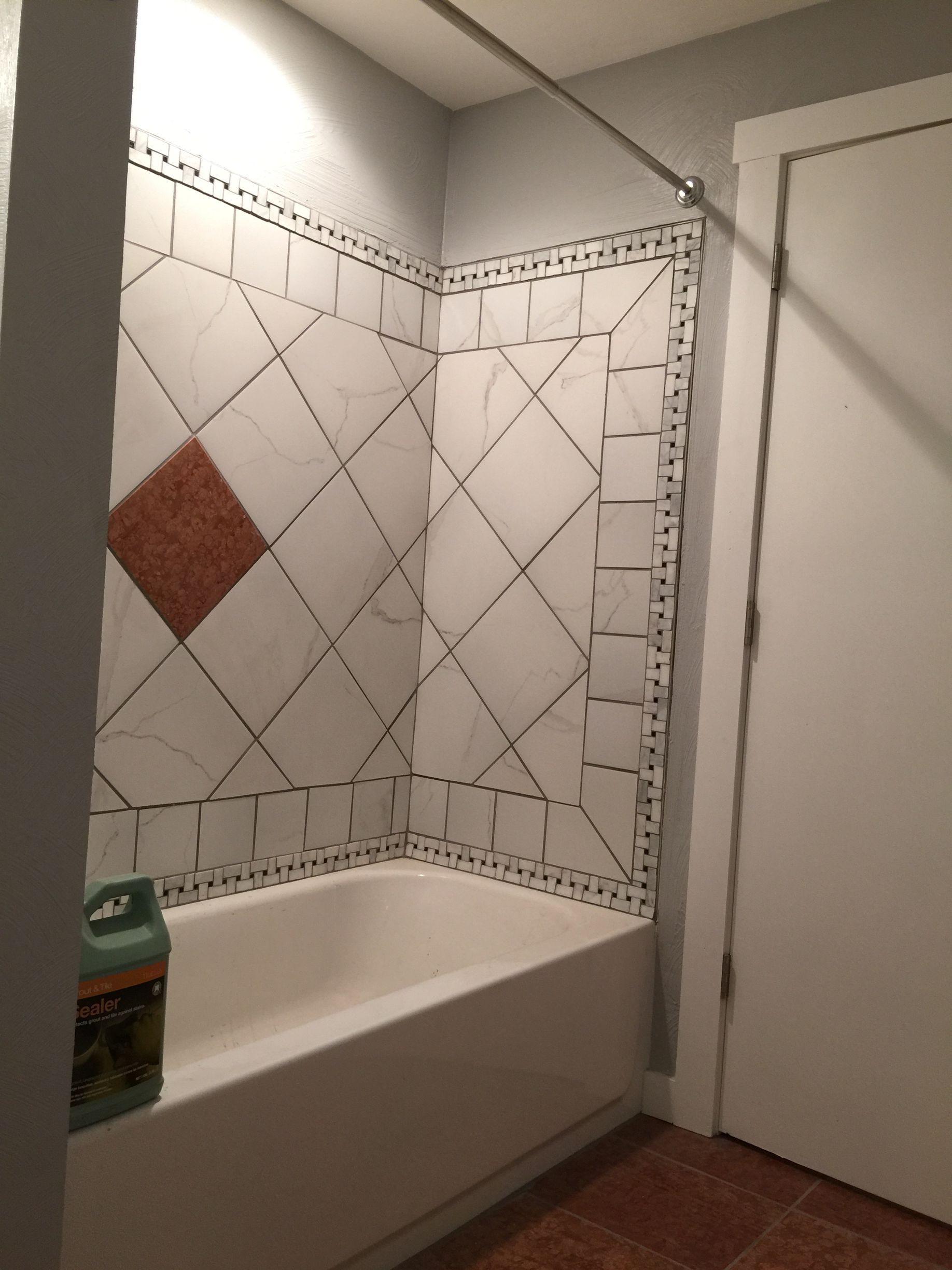 Bathroom with white tub and tile, and a closed white door on the right.