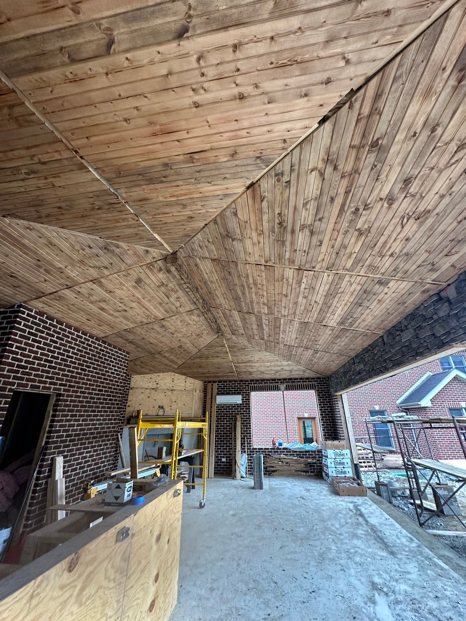 Wooden ceiling of an outdoor space, construction in progress, various tools and materials visible.