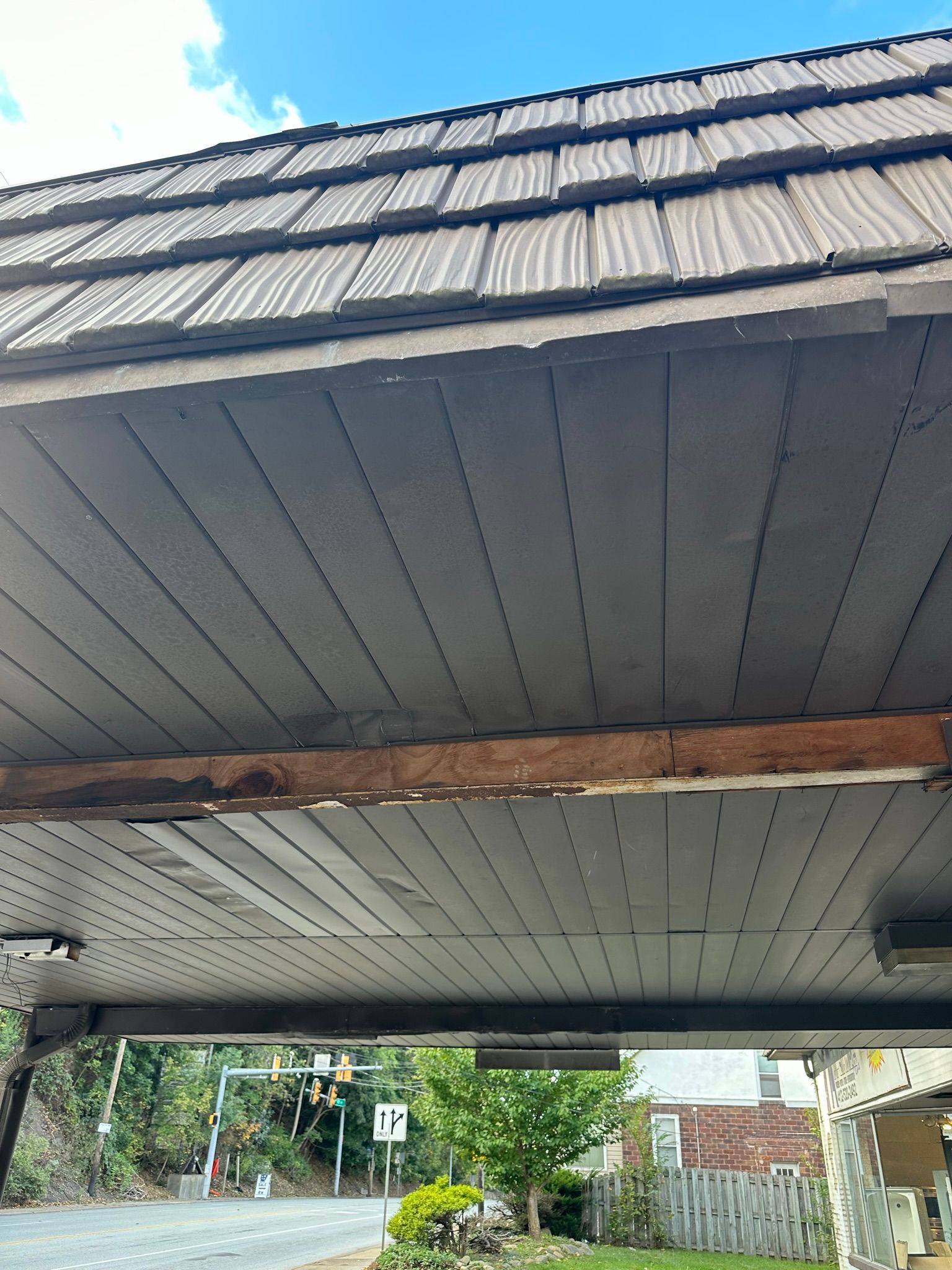 Overhead view of a wooden roof, with weathered boards and a street scene in the background.