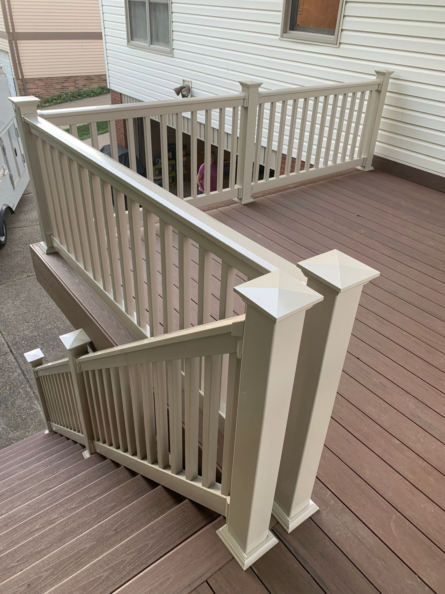 Wooden deck with stairs and beige railing.