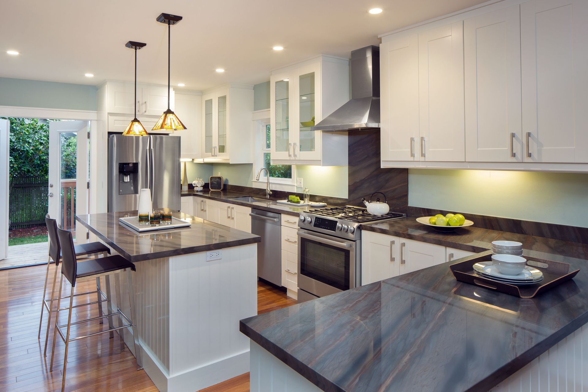 Modern kitchen with white cabinets, stainless steel appliances, and dark countertops.