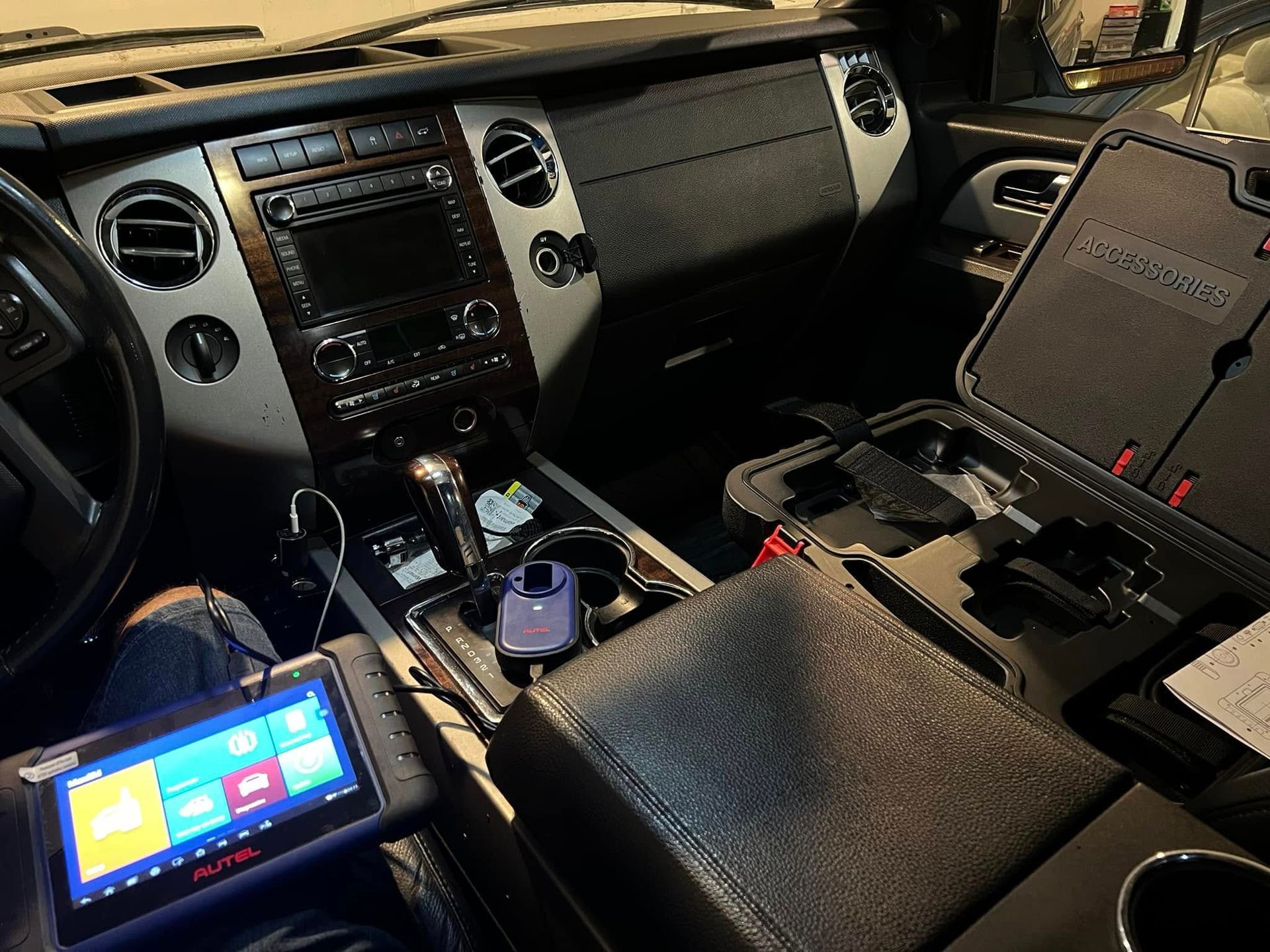 Car interior with dashboard, center console, a mounted tablet, and a small screen displaying colorful tiles.