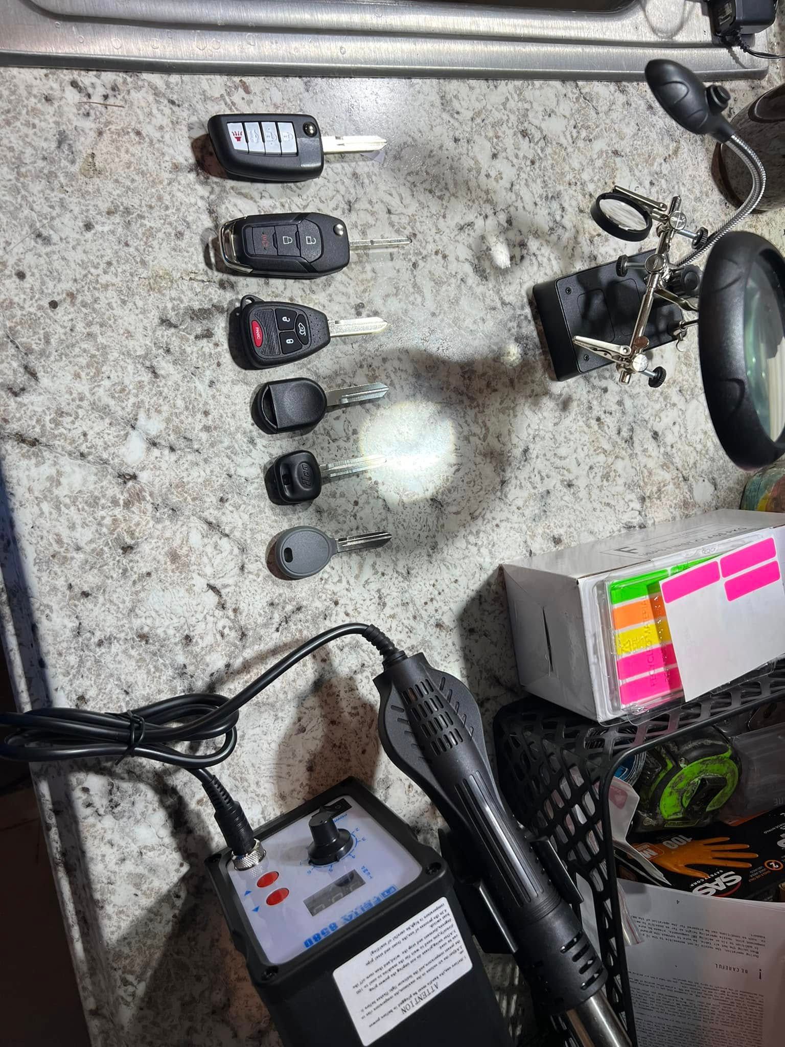 Assorted keys, cables, and small electronics arranged on a speckled tabletop.