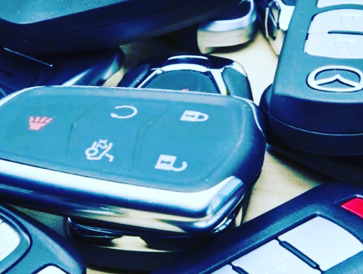 Close-up of several car key fobs with black, blue, and silver buttons on a table