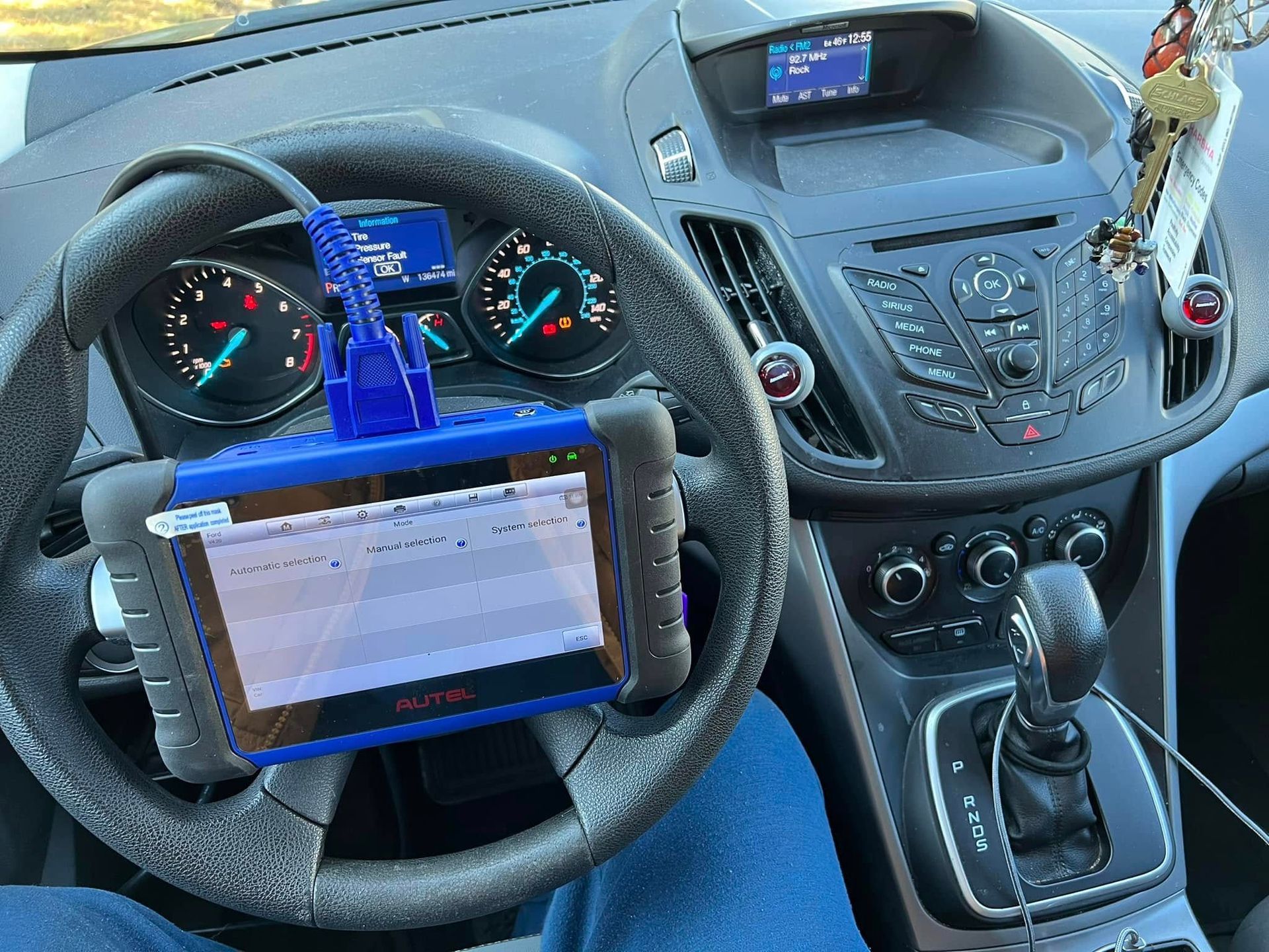 Car dashboard with steering wheel, mounted tablet, and manual gear shift inside the vehicle