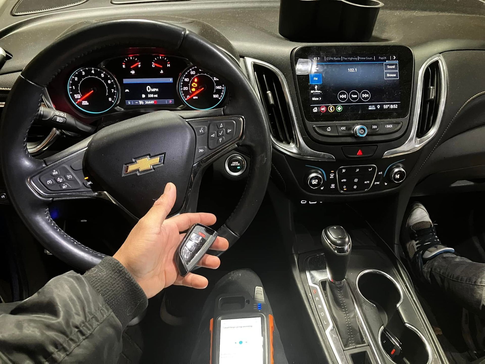 Driver’s seat view of a Chevrolet dashboard with a hand holding keys and the center console visible