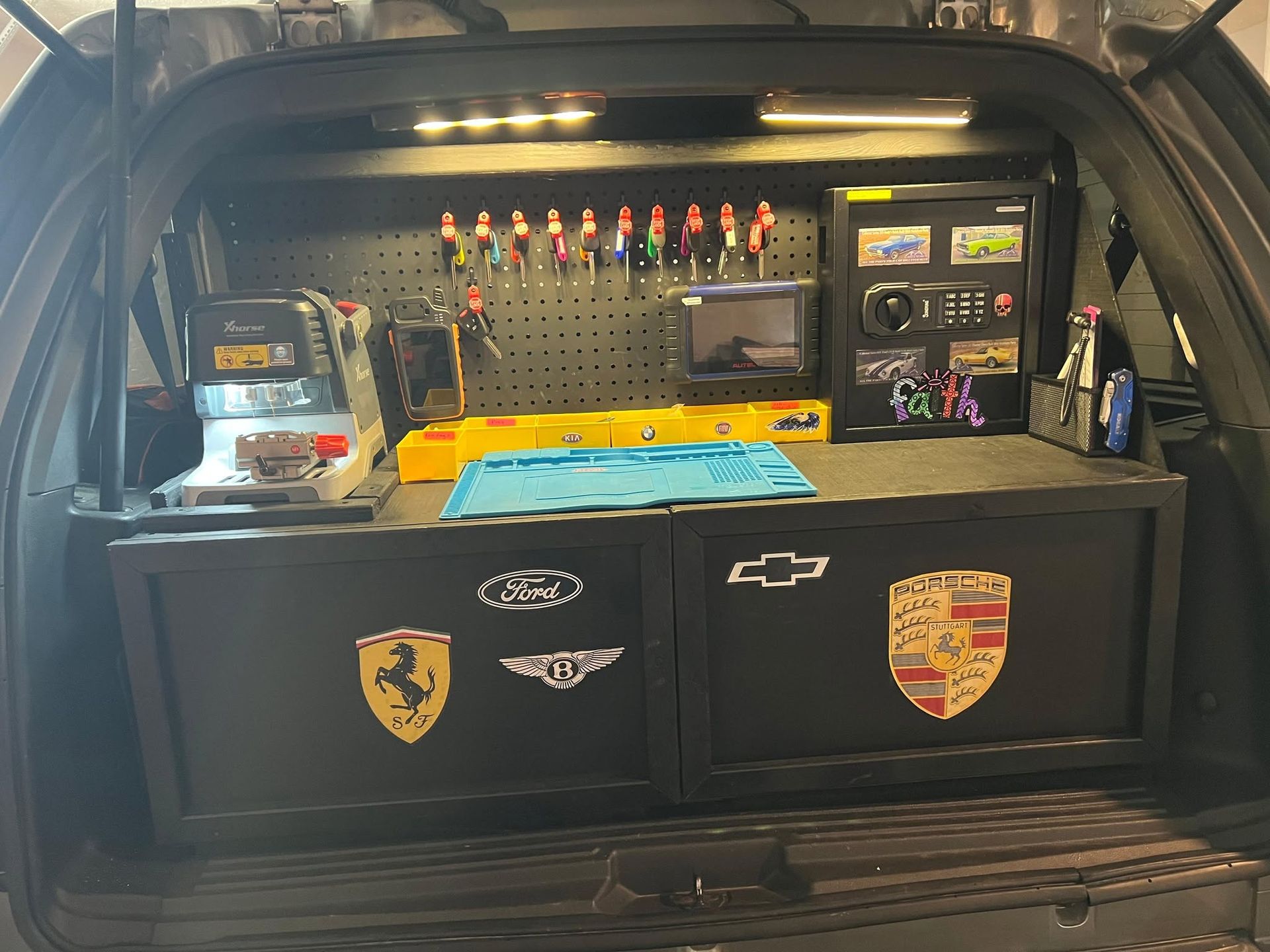 Car trunk turned into a tool storage setup with pegboard, lights, and sports team decals.