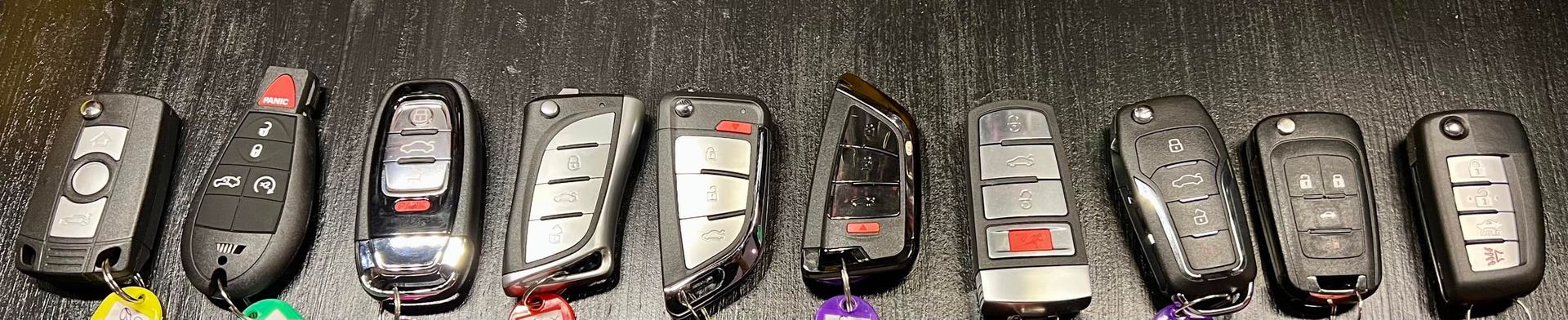 A row of small toy cars and SUVs lined up on a gray surface, viewed from above.