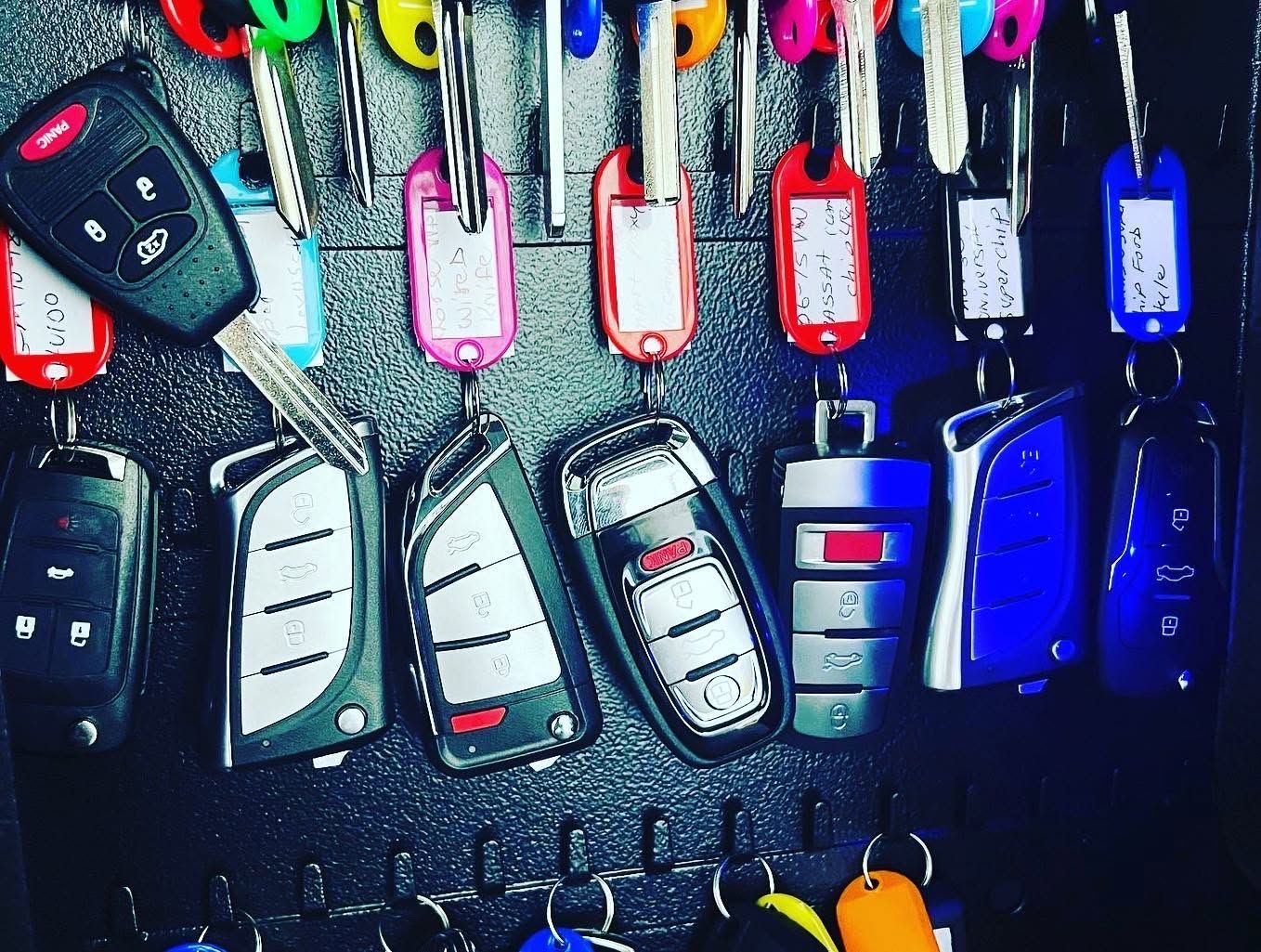 Several colorful car key fobs hanging on a wall display rack