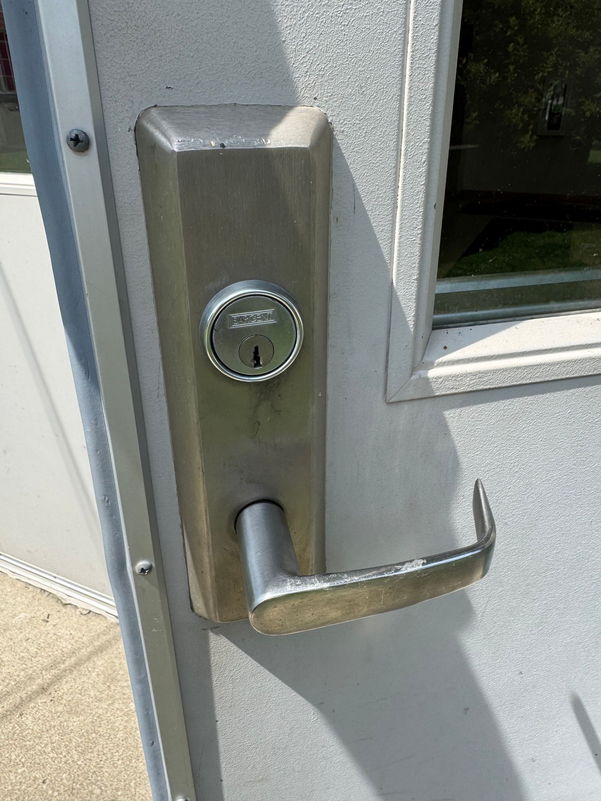 Close-up of a silver metal door handle and lock on a gray exterior door