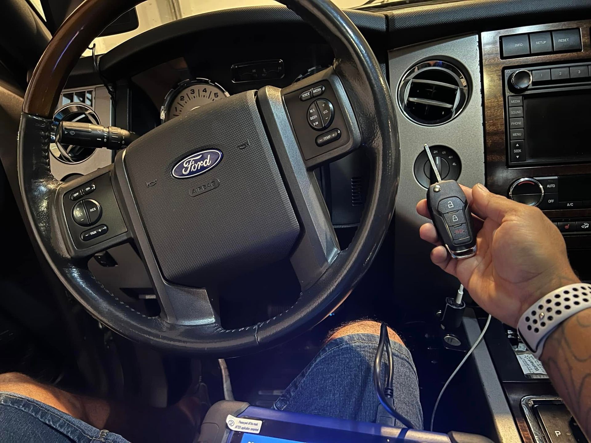 Driver’s seat of a Ford car; hand holding keys near the ignition and dashboard controls