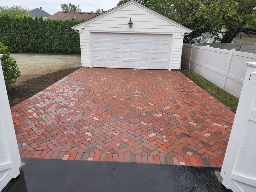 A red brick driveway leading to a  garage door