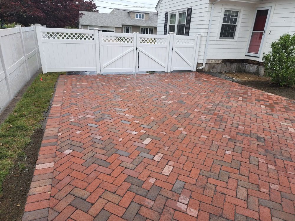 A red brick driveway with a white fence