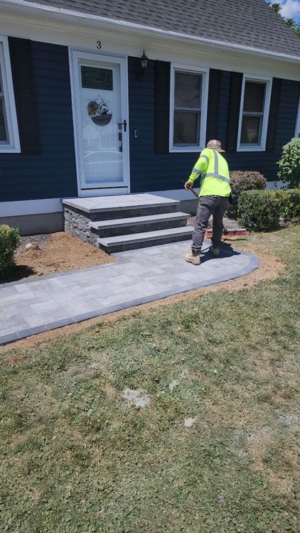 A Nelson Landscaping staff cleaning the walkway