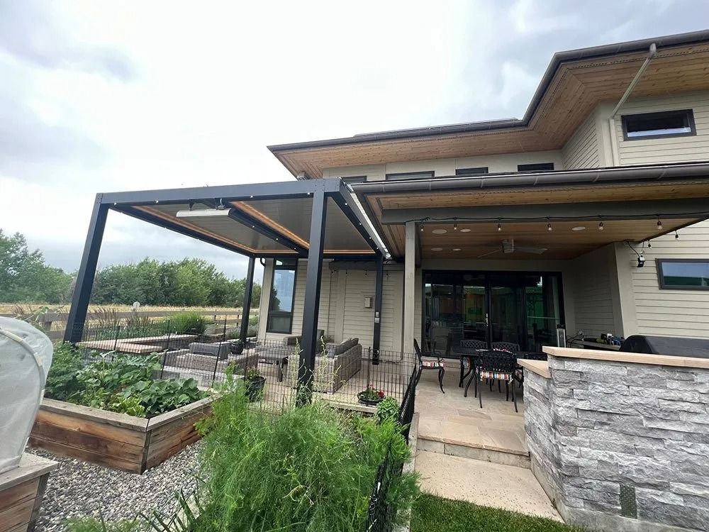 An outdoor patio with a modern pergola, seating area, and garden beds in front of a contemporary home.