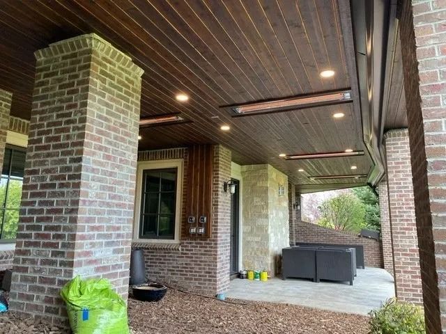 Outdoor patio with a wood ceiling, brick pillars, and recessed lighting. Two infrared heaters are mounted.