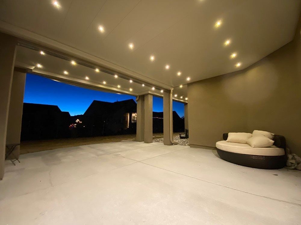 A spacious, well-lit patio at dusk with a curved couch and a view of the darkening sky.