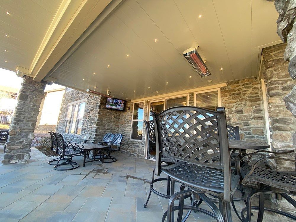 Outdoor patio with stone walls, metal furniture, and a ceiling with recessed lights and a mounted heater.