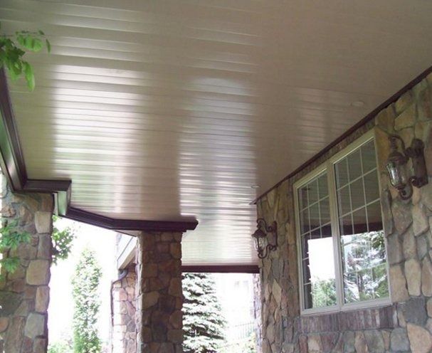 Tan-colored, ribbed ceiling on a porch with stone pillars and a window.