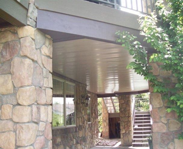 Stone columns and wall supporting a covered porch. Wooden stairs lead up in the background.