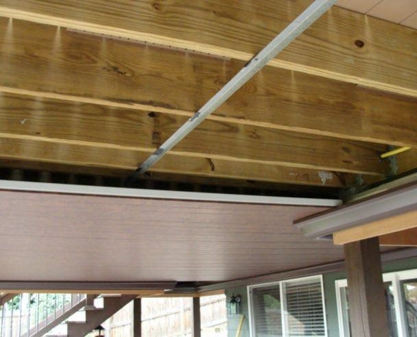 Underside of a wooden deck showing brown paneling with supporting beams and a metal track.