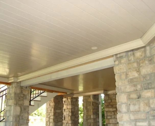 Beige, paneled ceiling with crown molding above a stone structure with pillars. A staircase is visible in the background.
