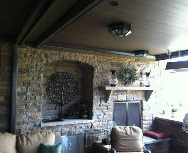 Outdoor stone fireplace with metal tree sculpture and seating.