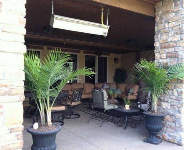 Outdoor patio with a seating area, stone columns, and potted palm trees. A mounted heater is visible on the ceiling.