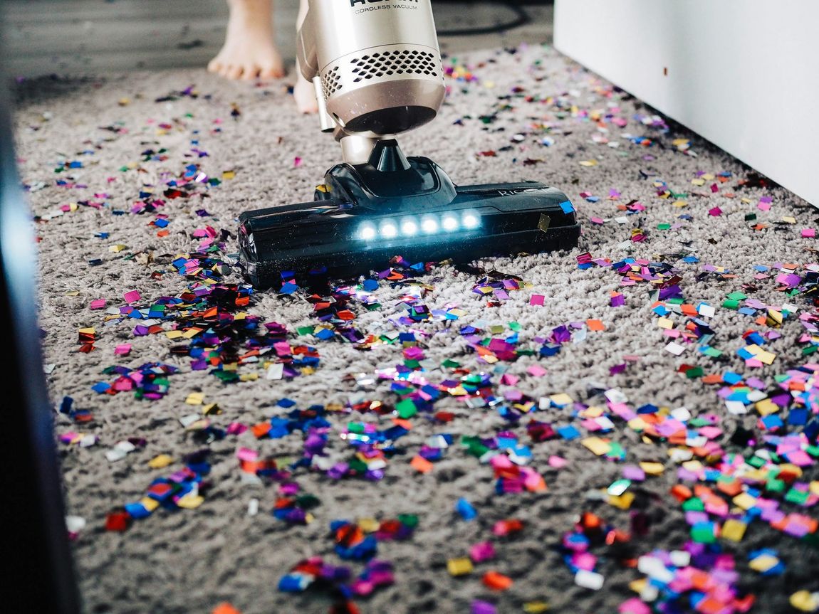 Carpet being professionally cleaned with a steam cleaning machine, revealing a visibly cleaner section.