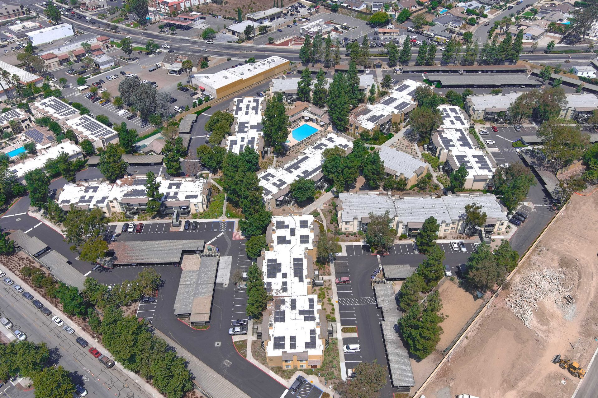 Aerial view of apartment complex with solar panels on roofs and a pool.