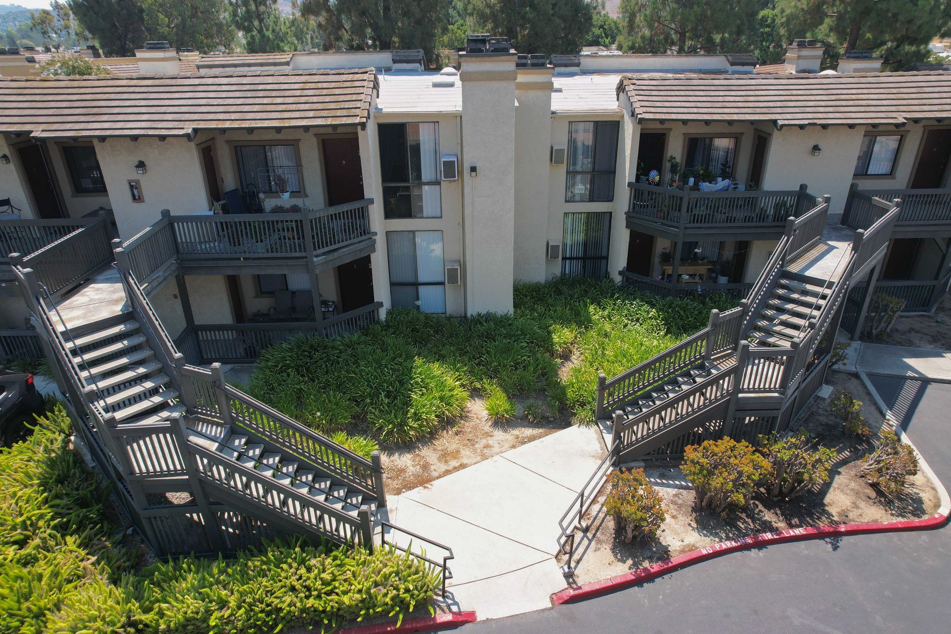 Apartment complex exterior with staircases, balconies, and landscaping.