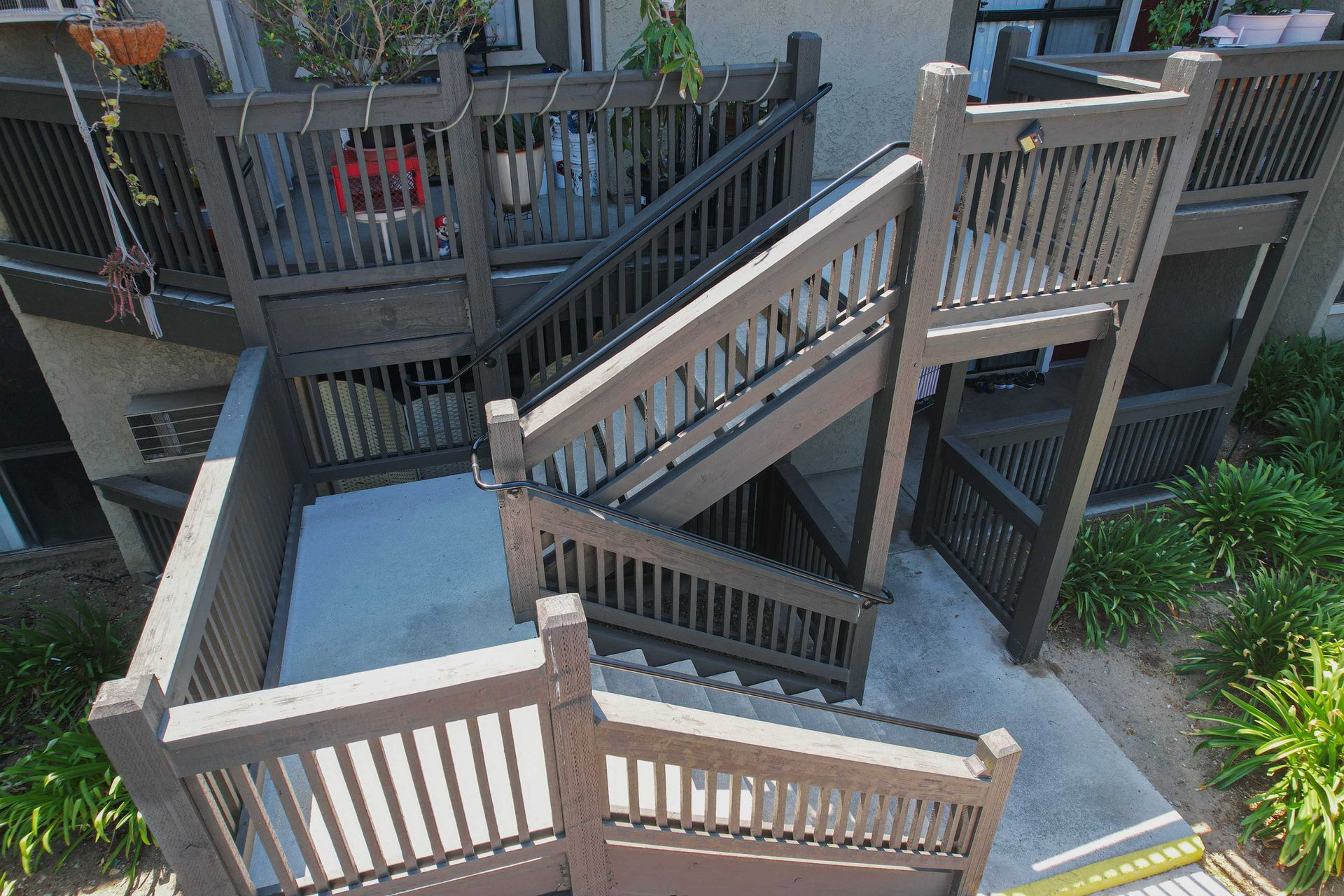 Brown outdoor staircase with wooden railings and multiple levels, leading to apartment units.