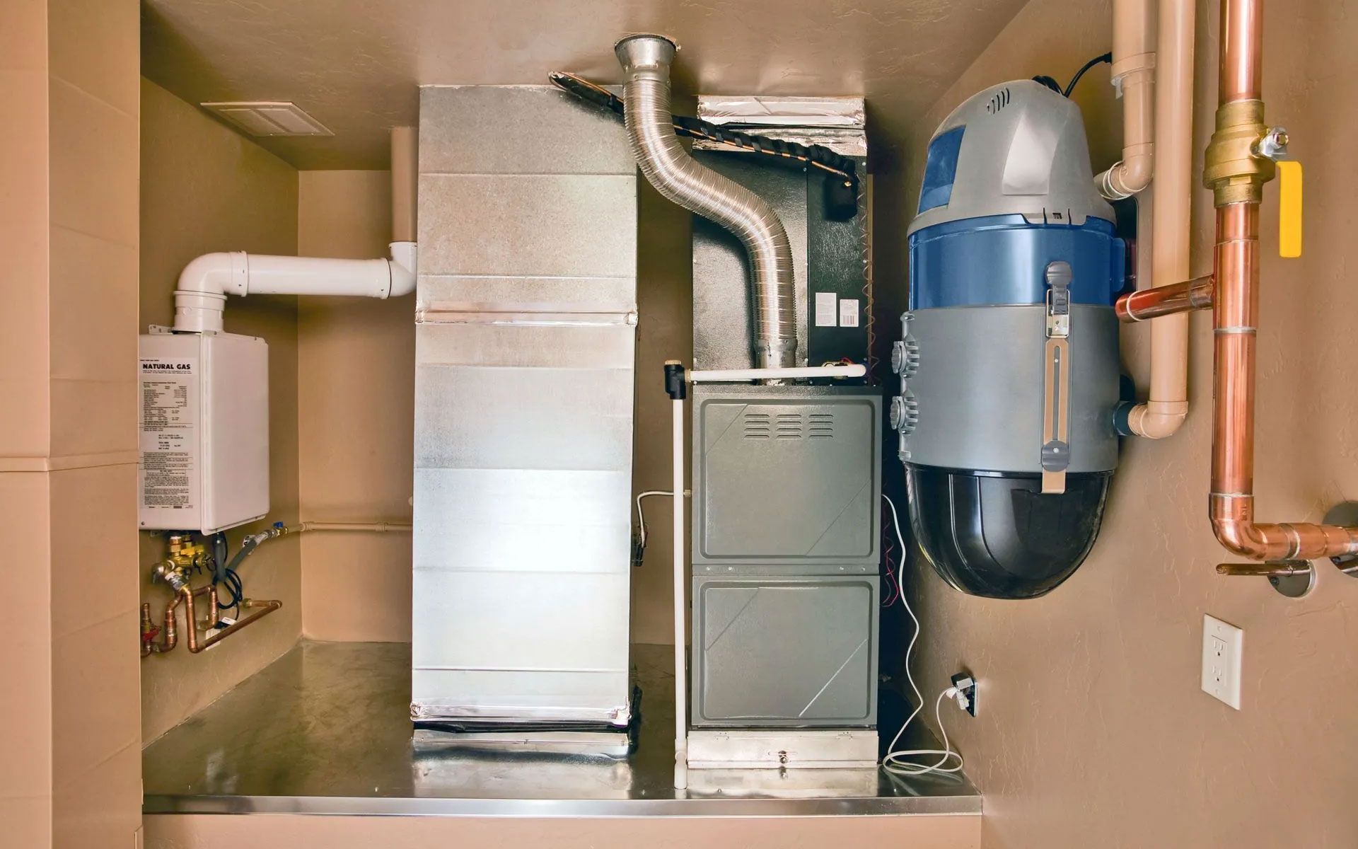 A mechanical room containing a water heater, furnace, ductwork, and a wall-mounted central vacuum unit.