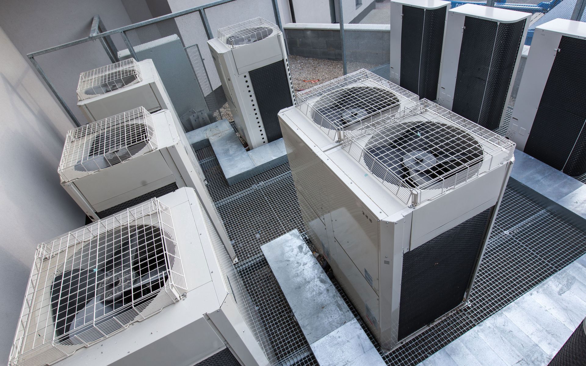 Several beige HVAC condenser units are arranged on a metal grated rooftop.