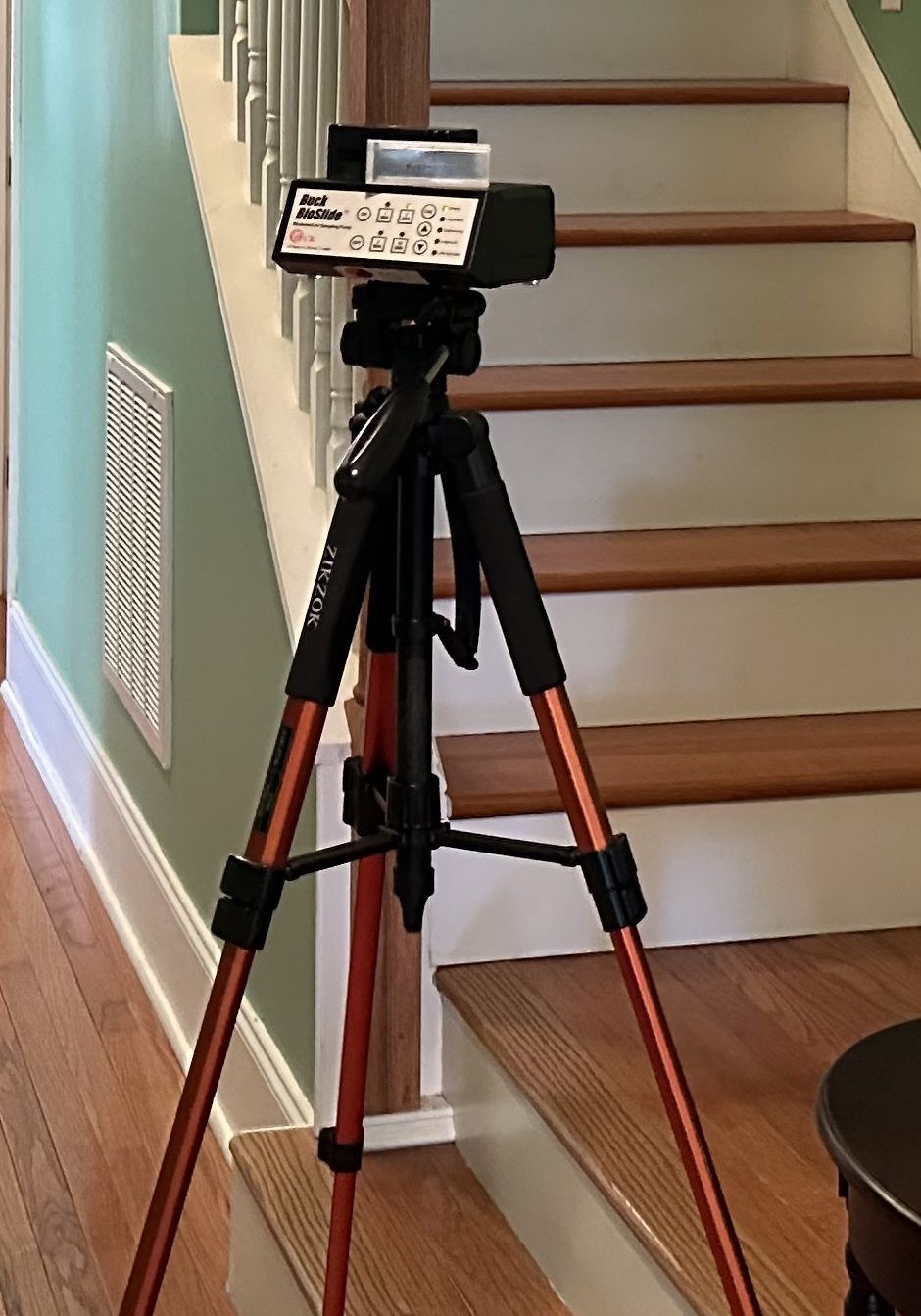 Camera on a red tripod aimed at a staircase in a home hallway.
