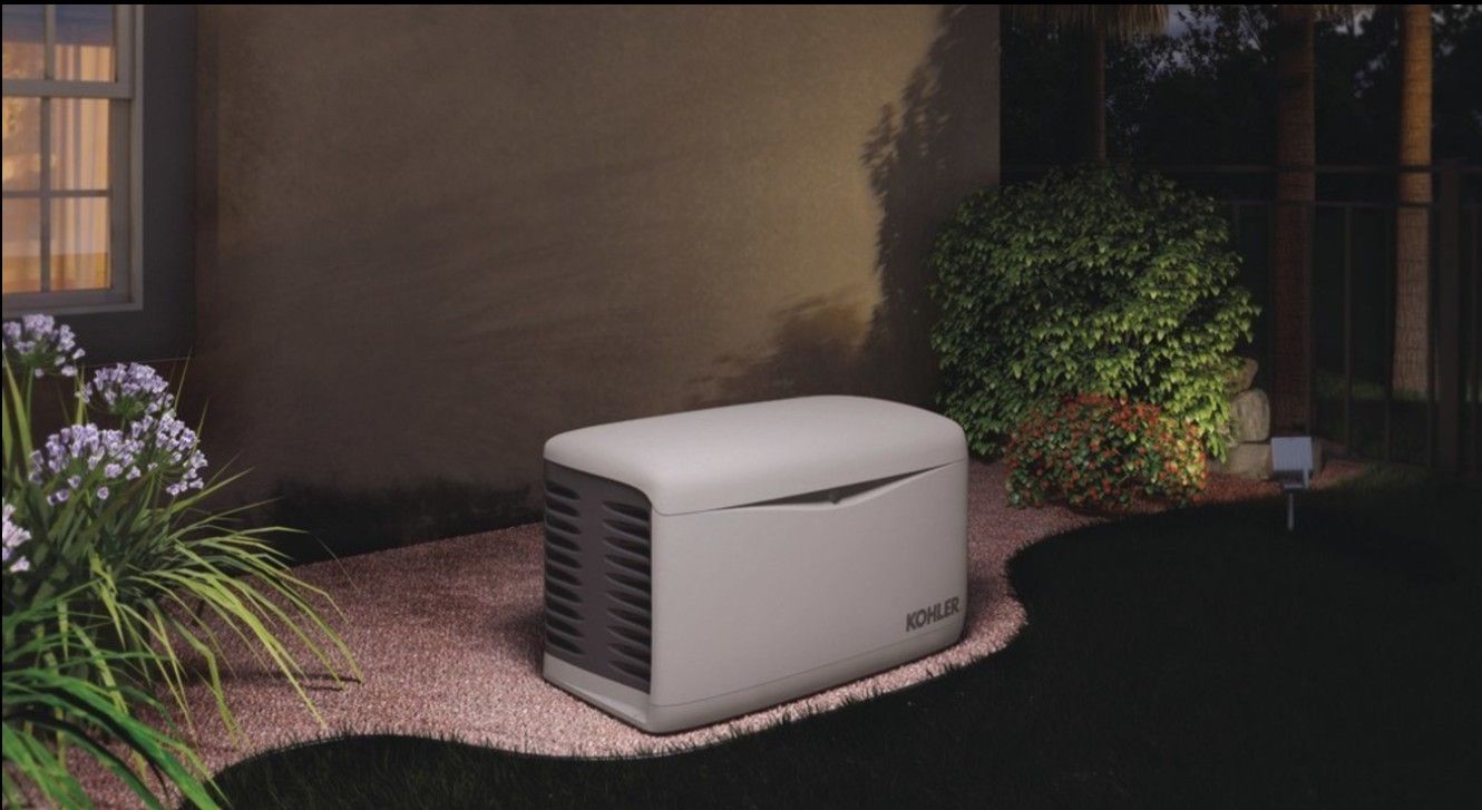 Generator beside a house at night, illuminated by soft lighting.