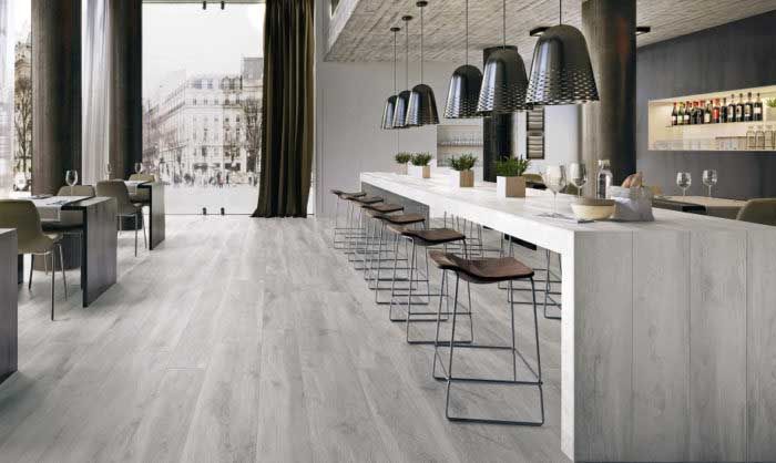 A kitchen with a long counter and stools and a large window.