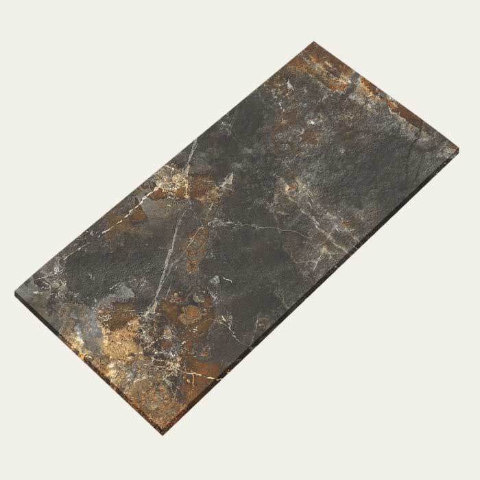 A black and gold tile is laying on a white surface