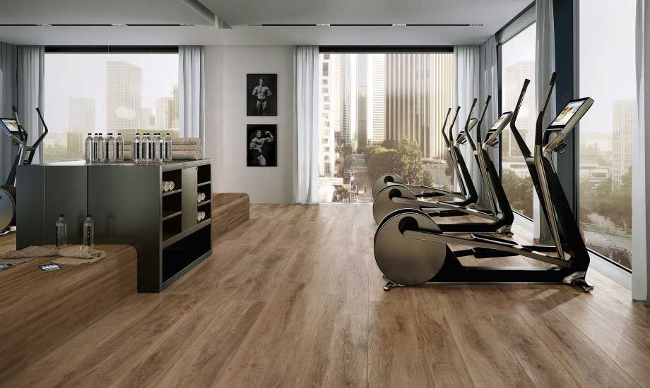 A gym with a lot of exercise equipment and a wooden floor.