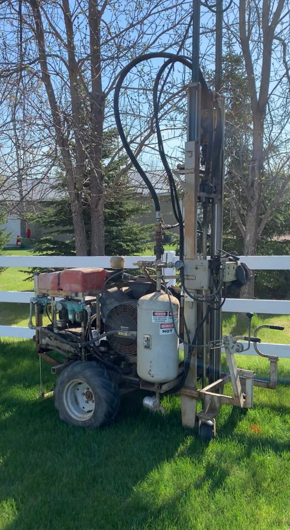 A machine is sitting in the grass next to a fence.