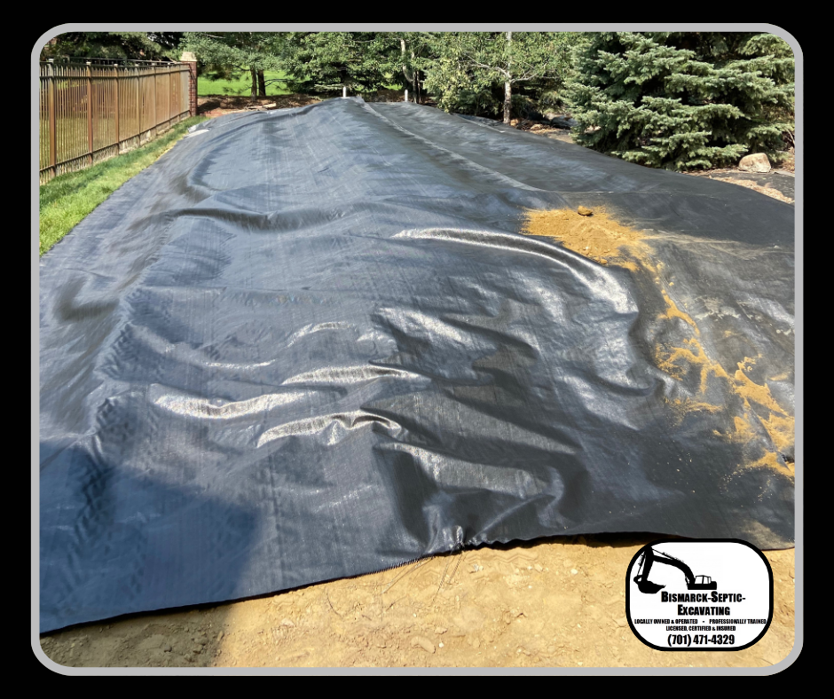 A large black tarp is sitting on top of a dirt field.