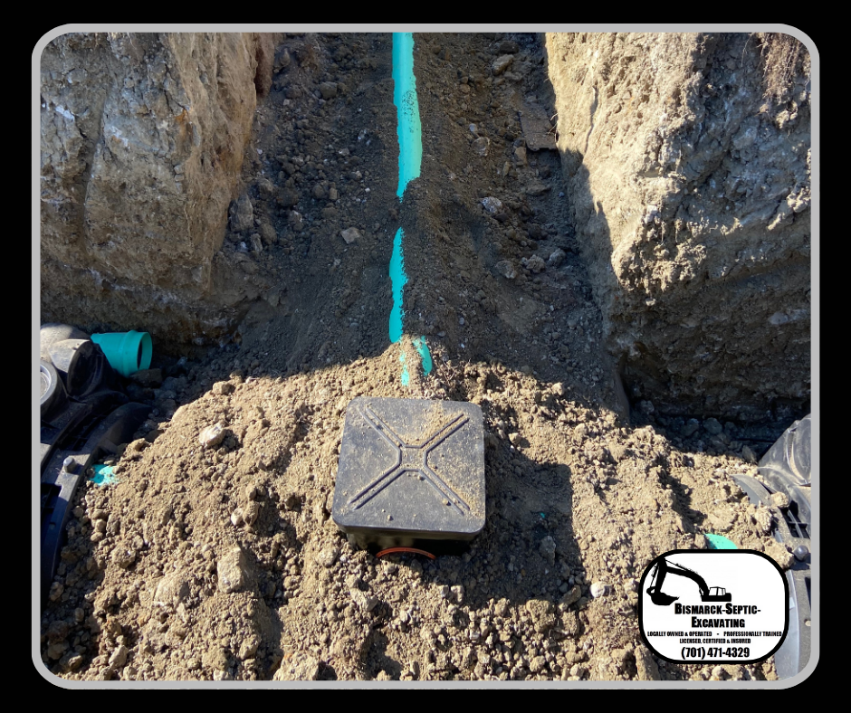 A black box is sitting in the dirt next to a blue pipe.