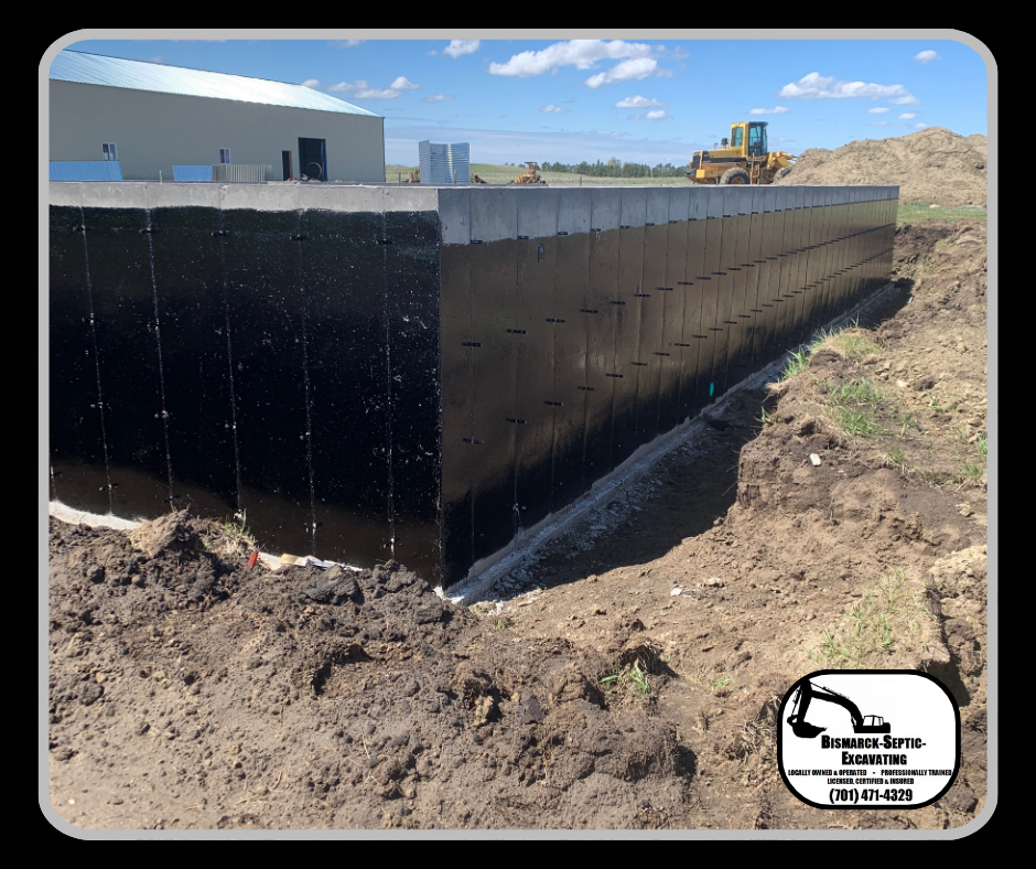 A large wall is being built in the dirt in front of a building.