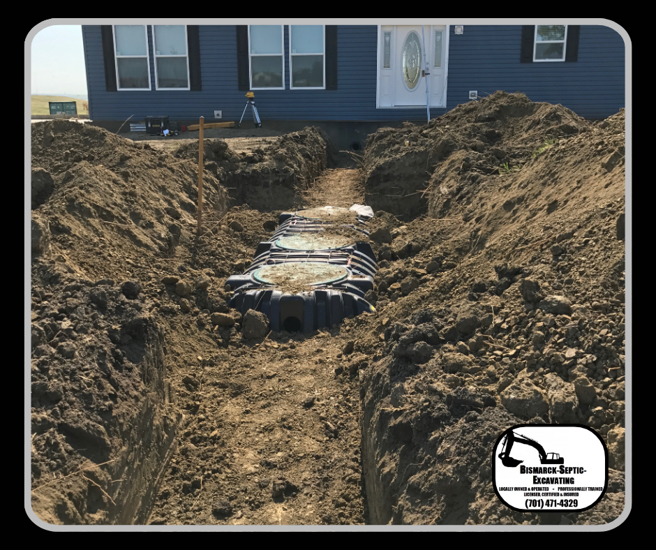 A septic tank is being installed in the dirt in front of a house.